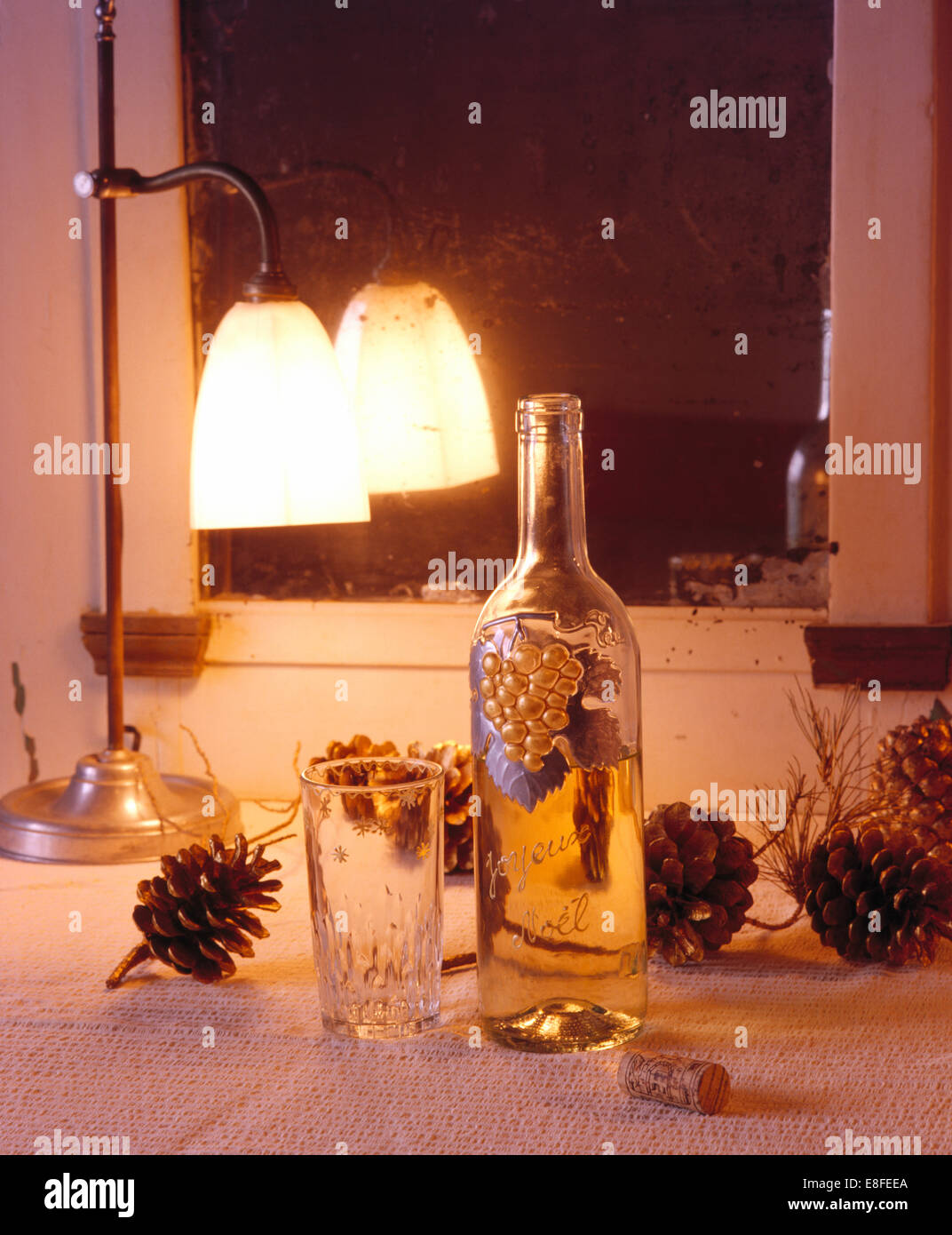 Close-up of lighted lamp and hand-painted glass bottle on table with festive pine cones Stock Photo