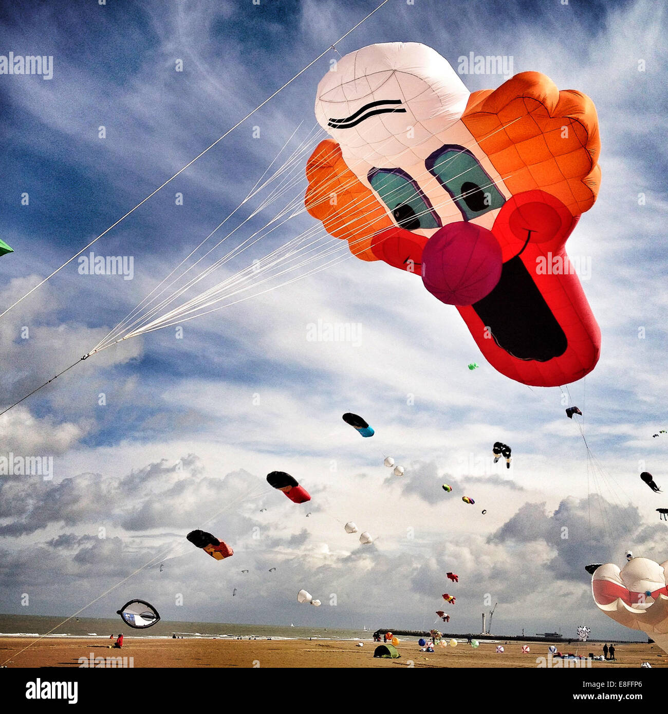 UK, Large Clown kite flying over beach Stock Photo