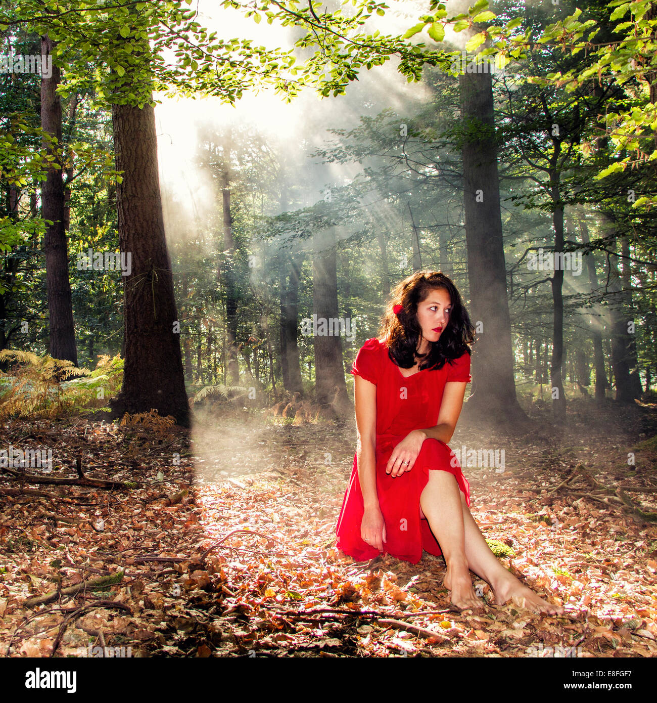 Woman sitting in forest in sunlight Stock Photo