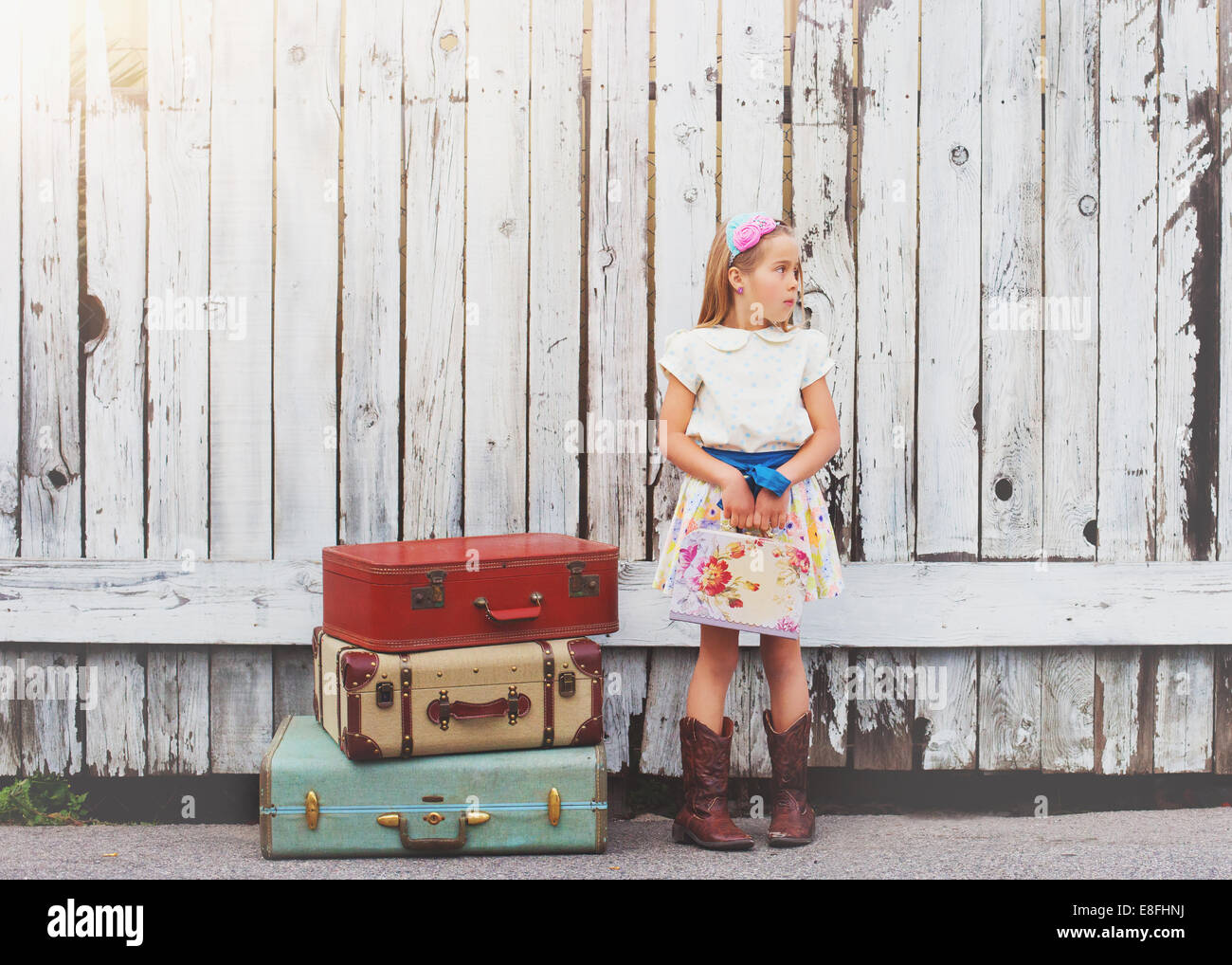 Girl standing by a stack of suitcases outdoors, California, USA Stock Photo