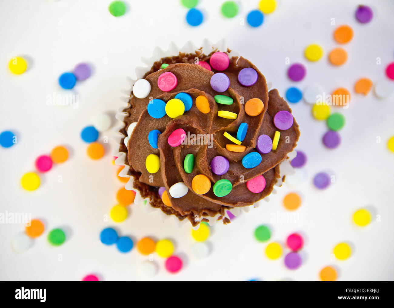 Chocolate cupcake covered with buttercream frosting and multi coloured sprinkles Stock Photo