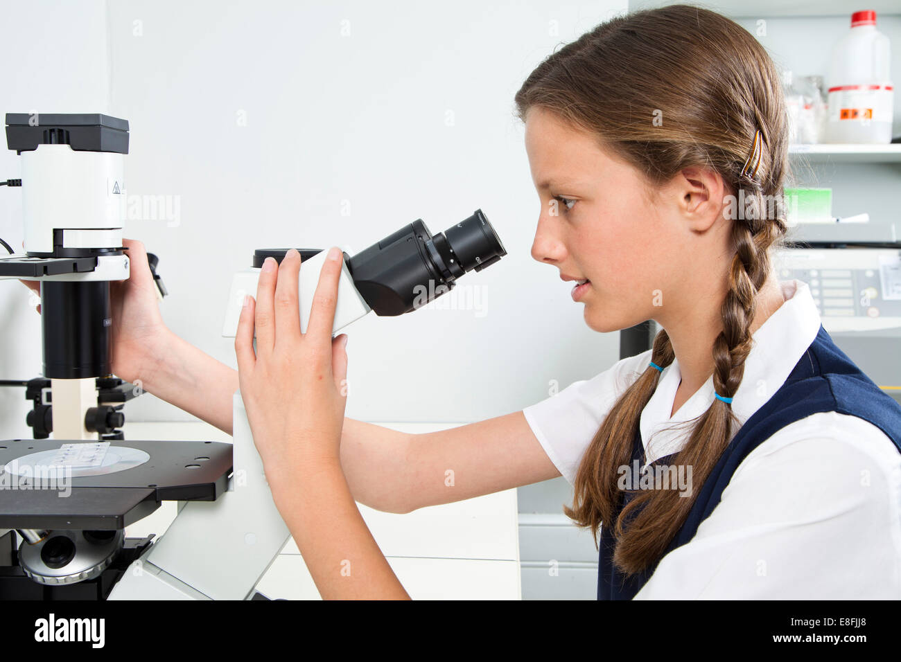 Schoolgirl sitting in a classroom looking through a Microscope Stock ...