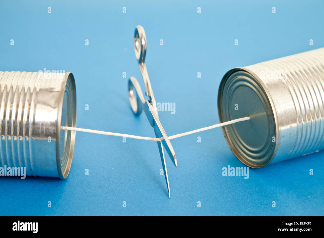 Scissors cutting Tin Can phone string Stock Photo