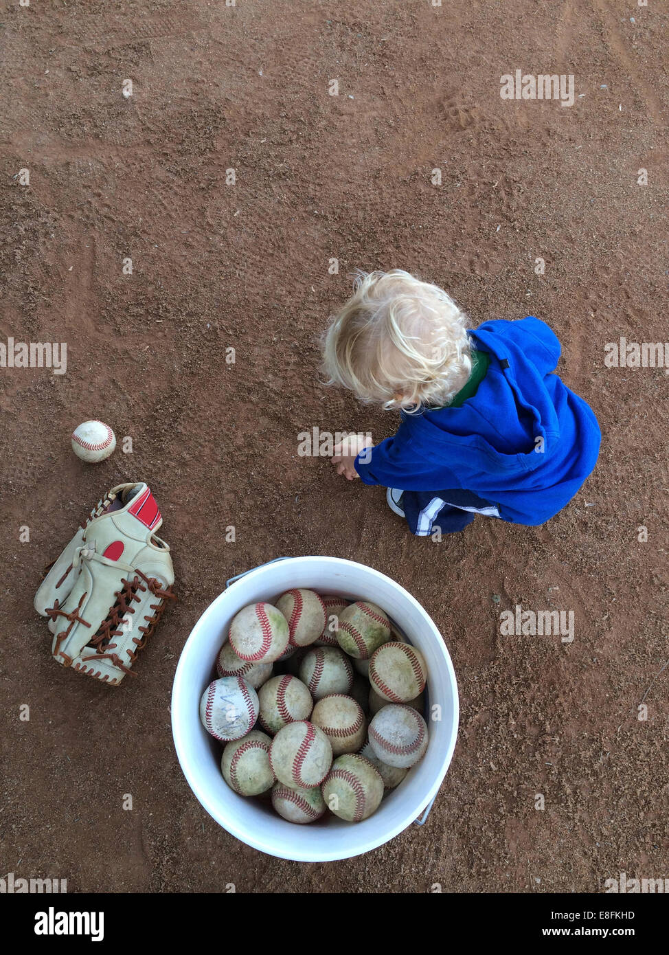 Boy collecting baseball balls in a ball bucket hires stock photography