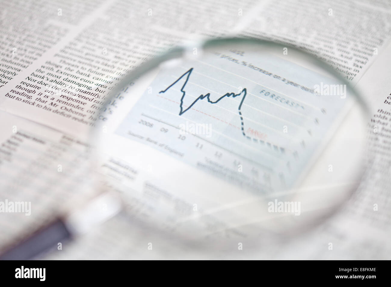Close-up of a magnifying glass focused on financial market graph Stock Photo
