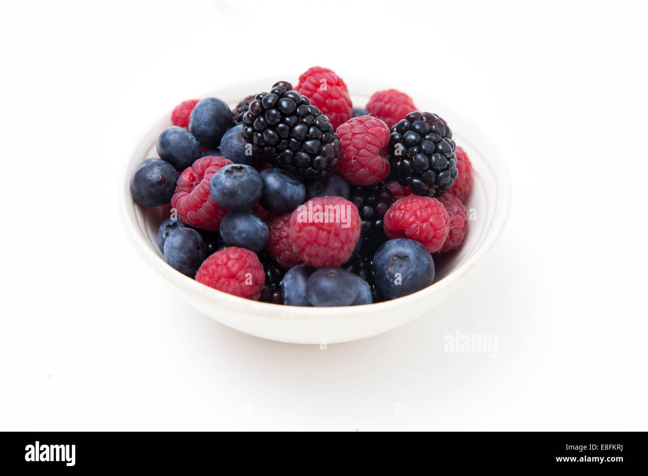 Close-Up of a bowl of fresh raspberries, blueberries and blackberries on a table Stock Photo