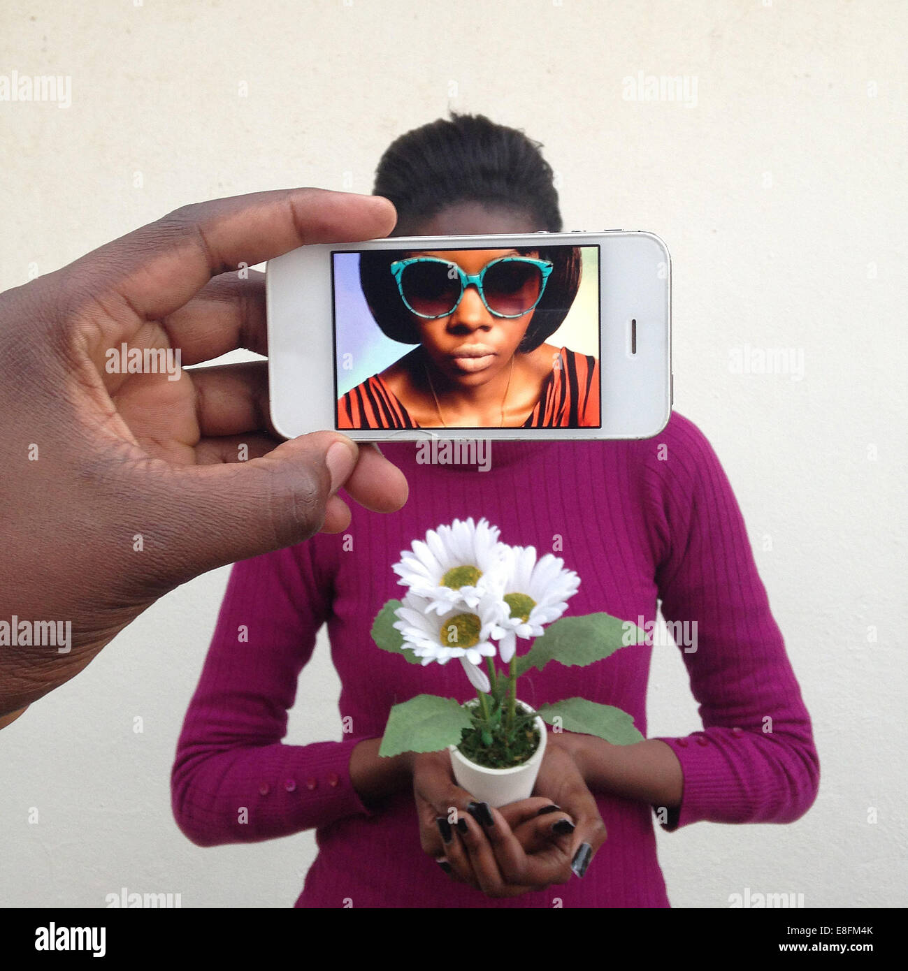 Man photographing a young woman using a mobile phone and seeing her alter ego on the screen Stock Photo