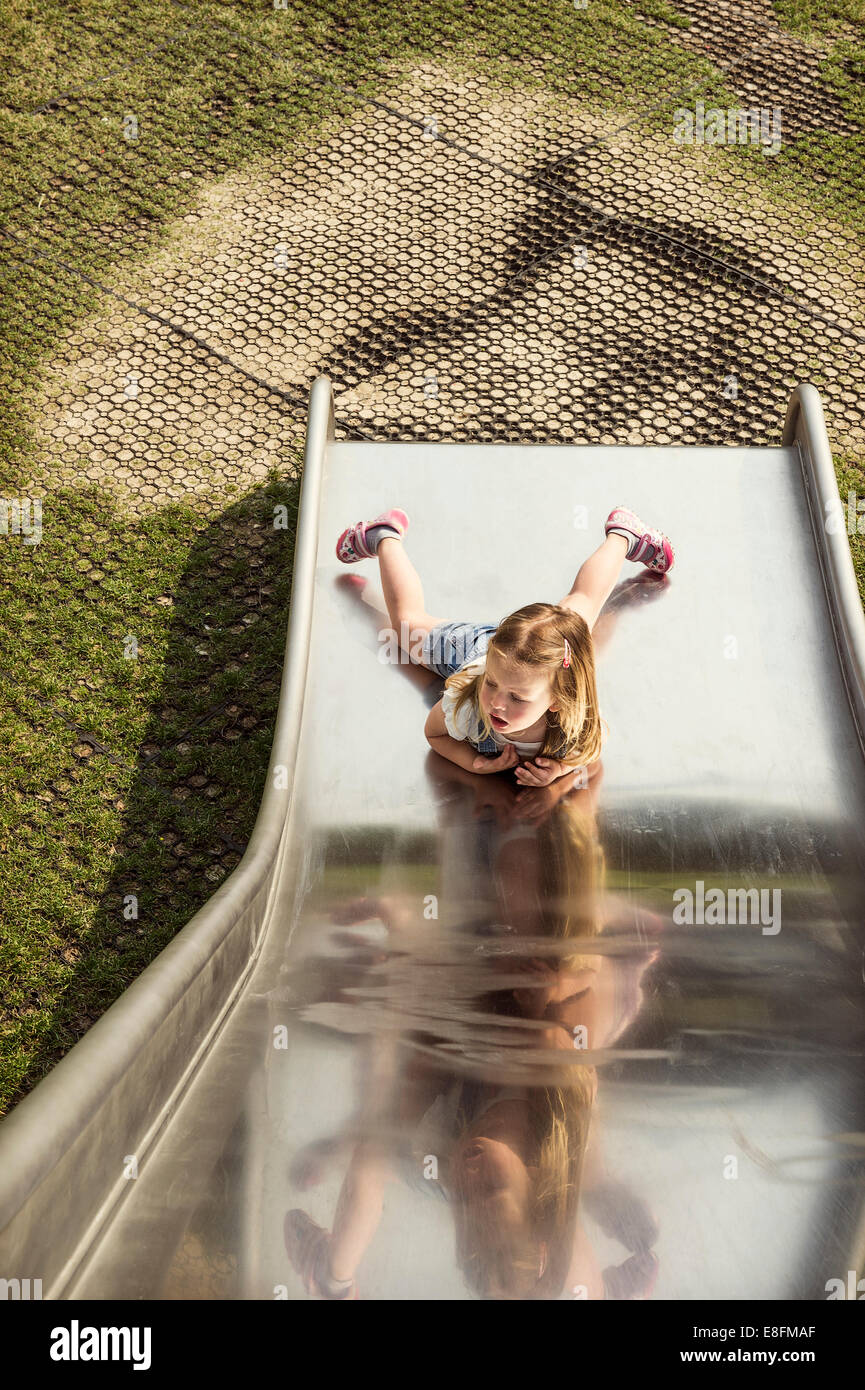 Girl lying at the bottom of a slide in playground Stock Photo - Alamy