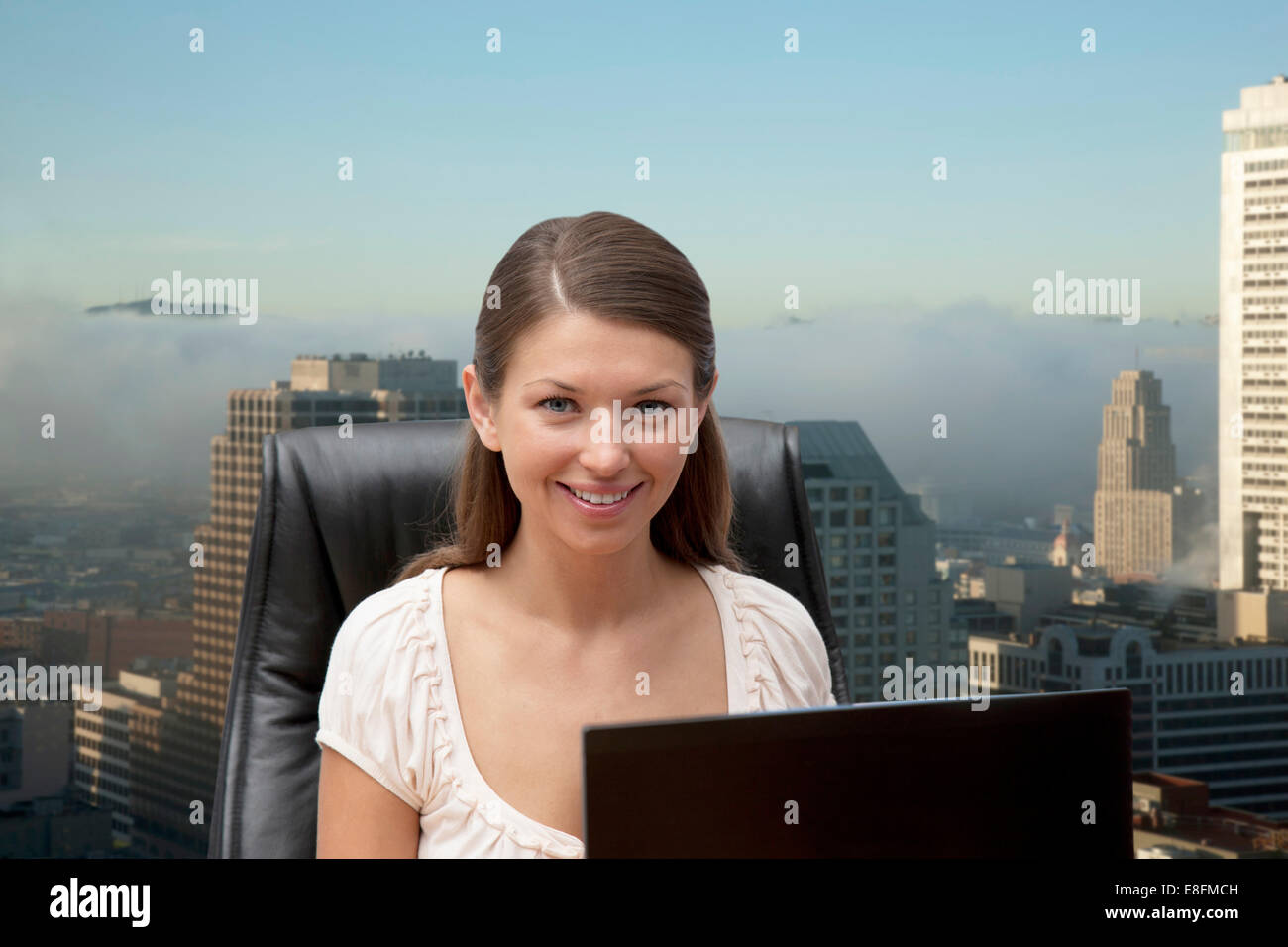 Portrait of young businesswoman in office with office buildings in background Stock Photo