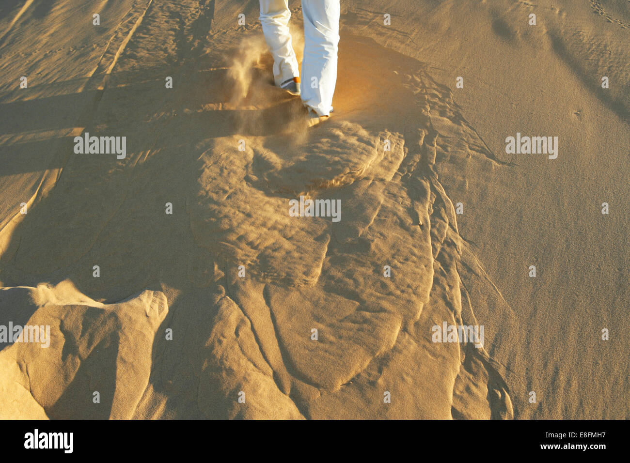 Man running up sand dune Stock Photo