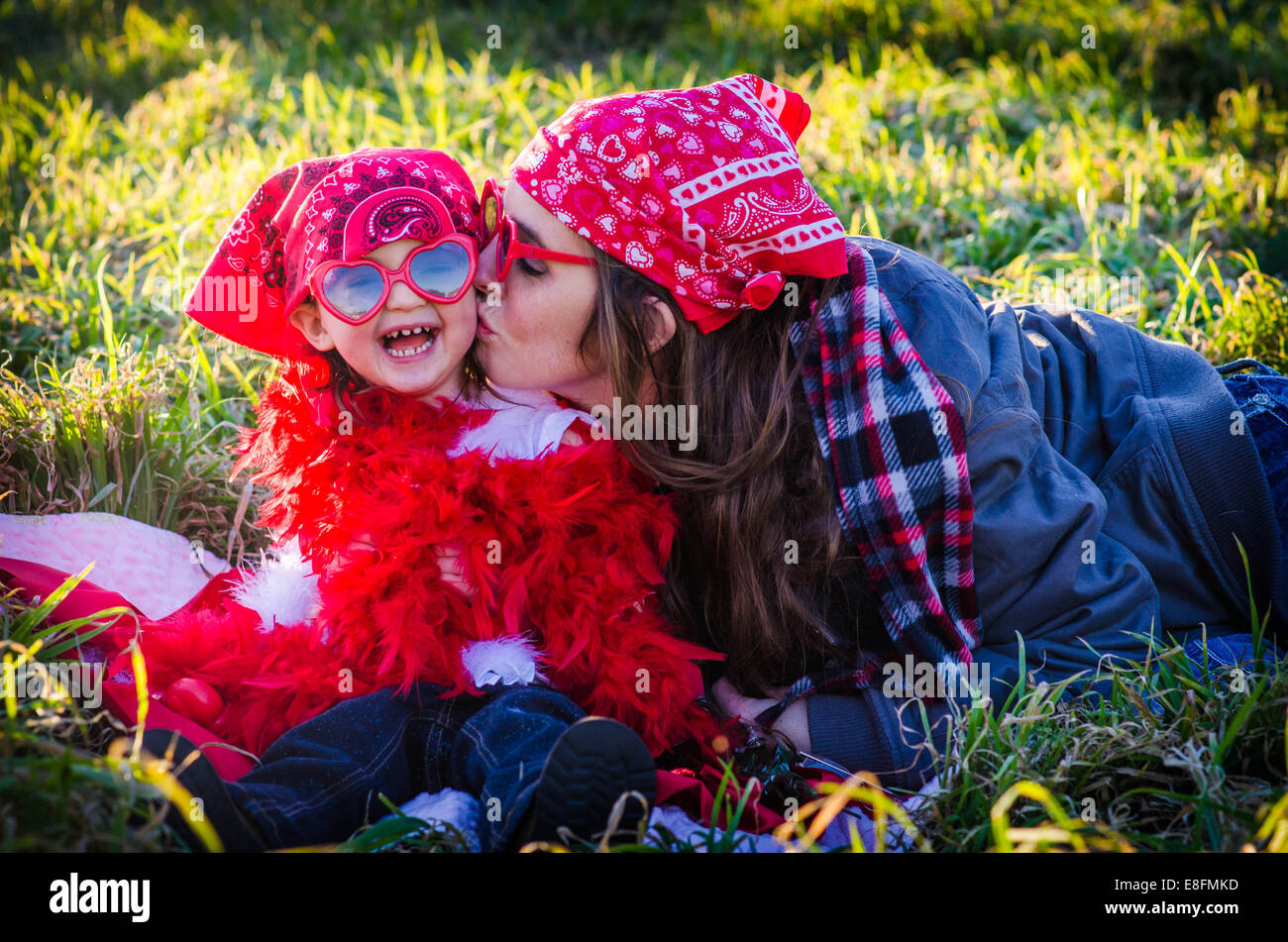 Woman sitting in a meadow kissing her daughter, Texas, USA Stock Photo