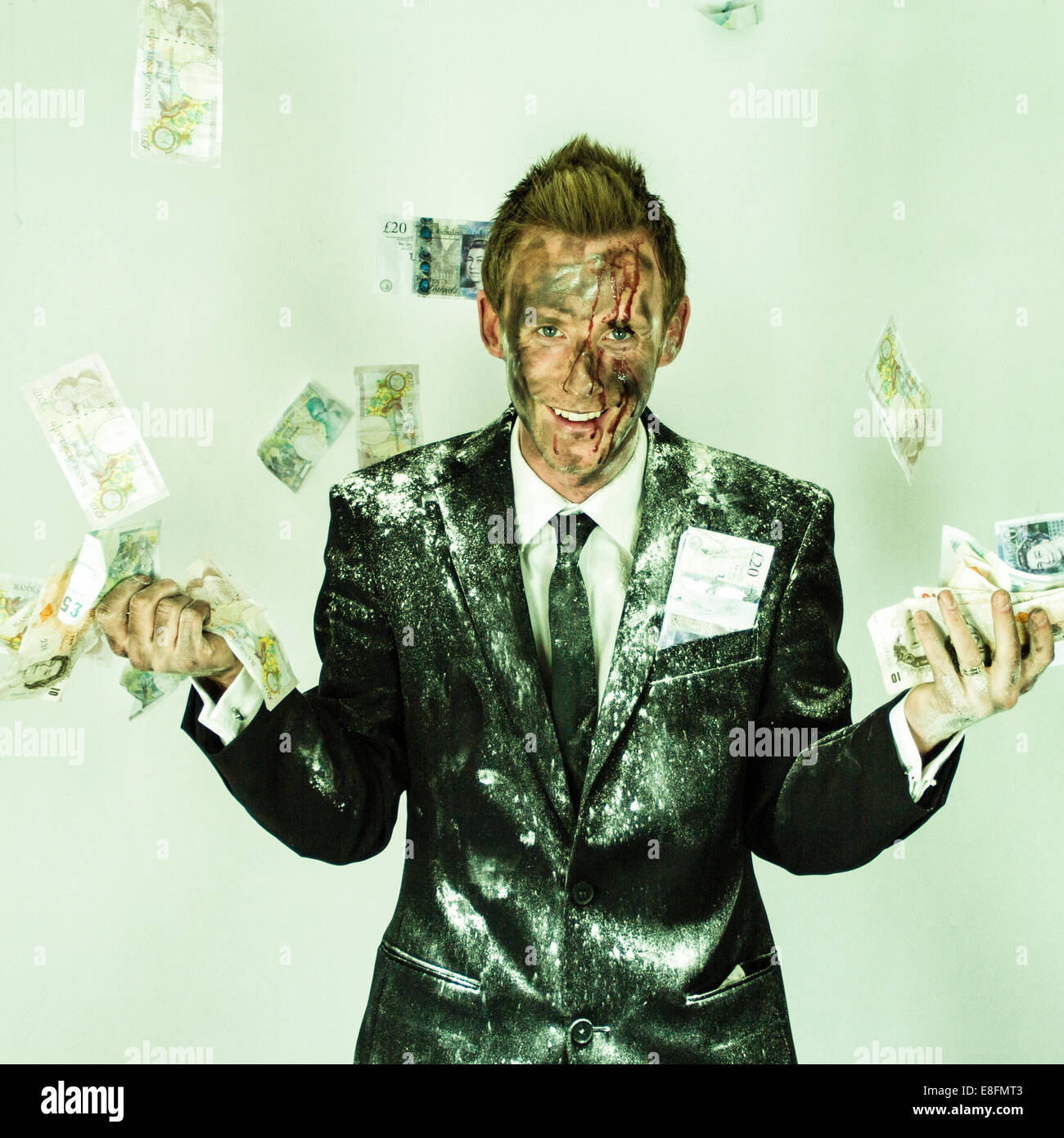 Bloodied man in a dirty suit throwing money in the air Stock Photo