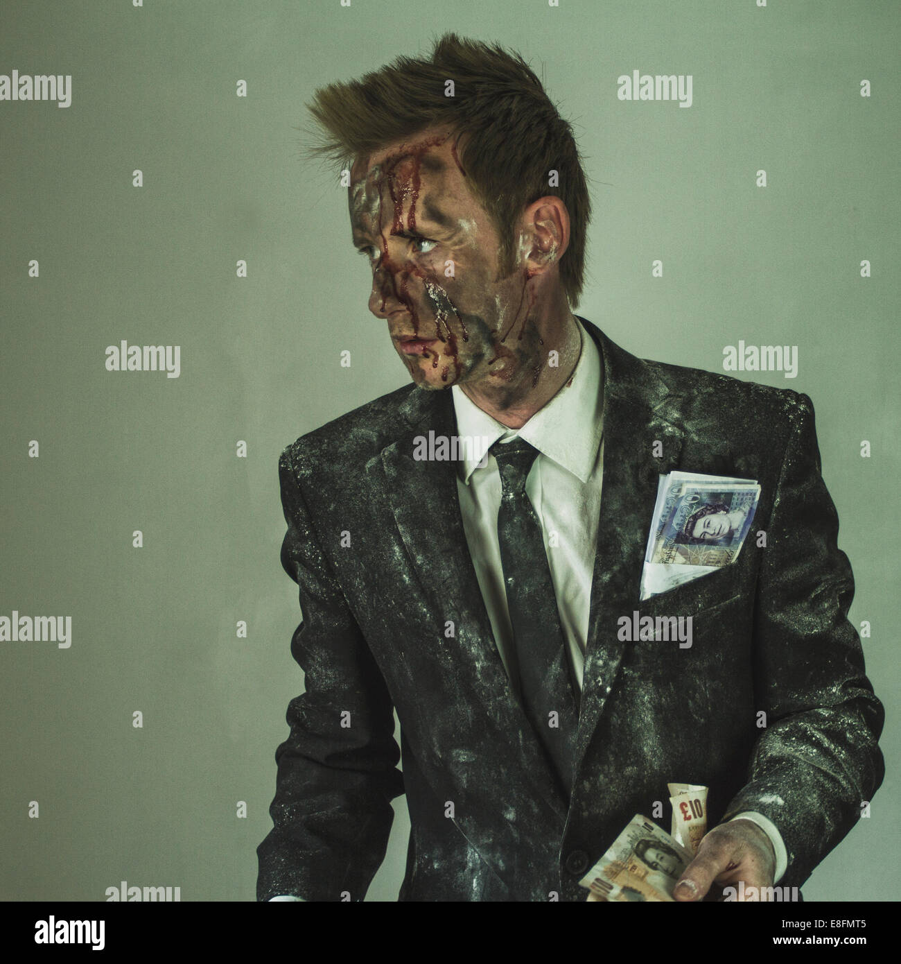 Bloodied man in a dirty suit holding a handful of money Stock Photo