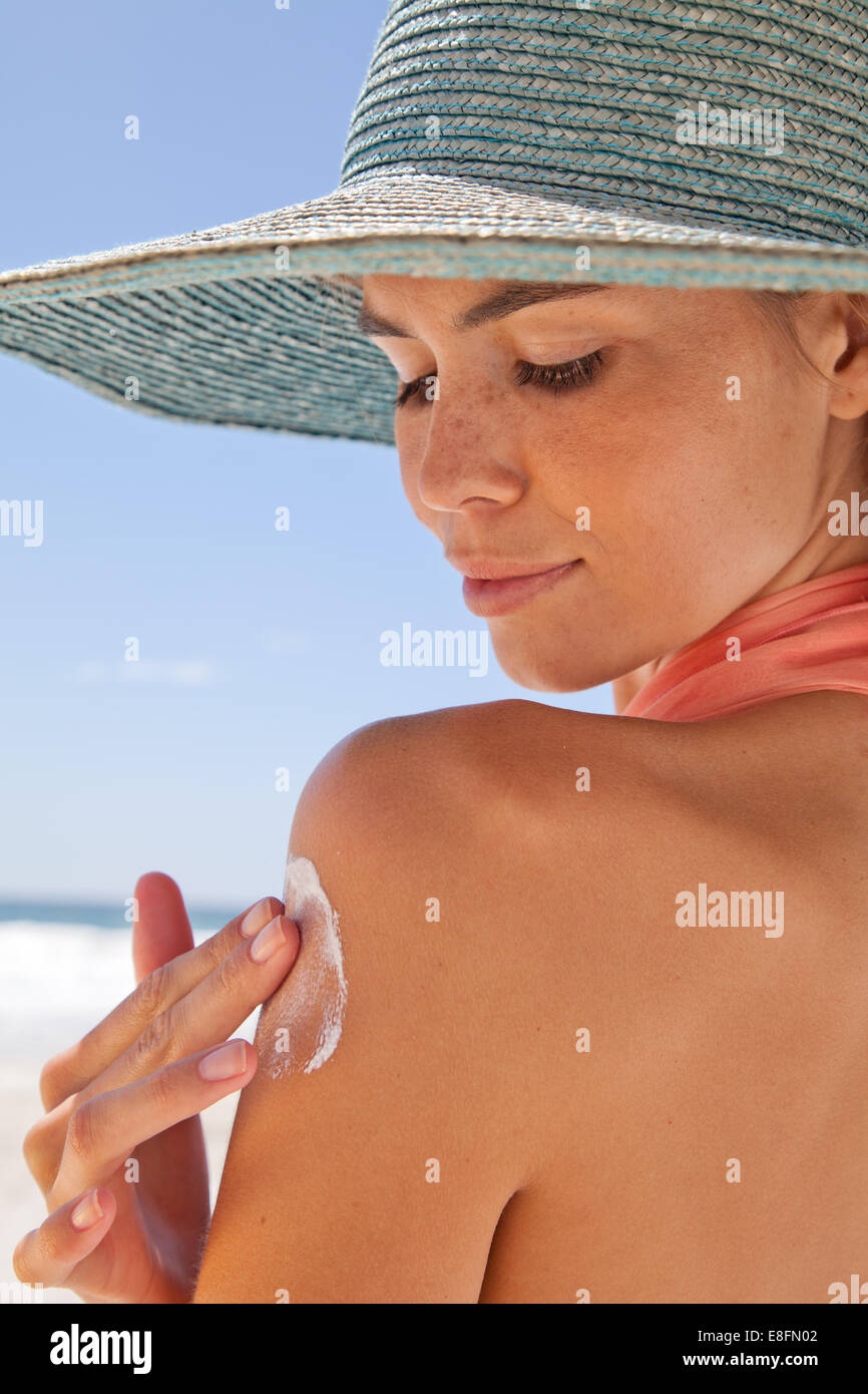 Close up of young woman on the beach applying sun cream, Cape Town, Western Cape, South Africa Stock Photo