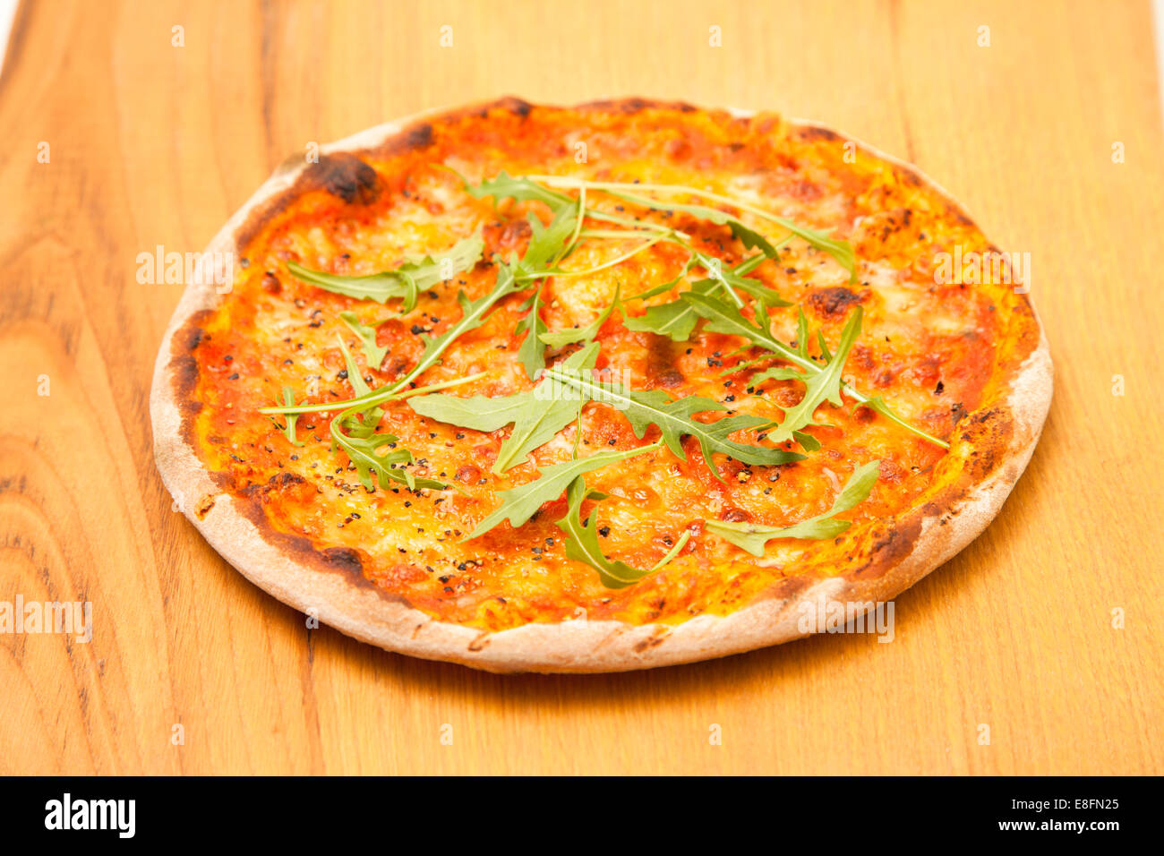 Margherita Pizza with chilli flakes and rocket on wooden table Stock