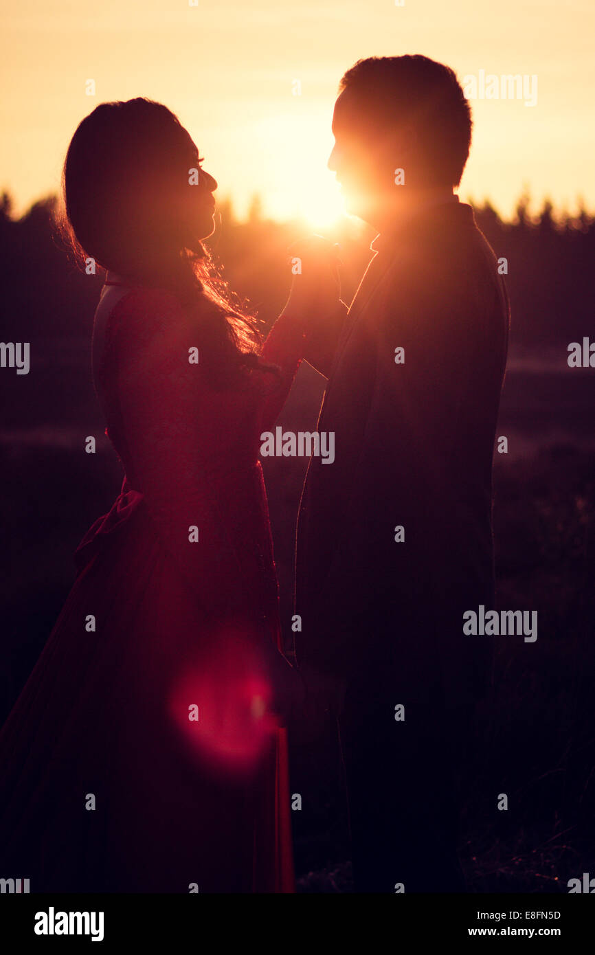 Silhouette of couple standing in meadow at sunset hi-res stock ...