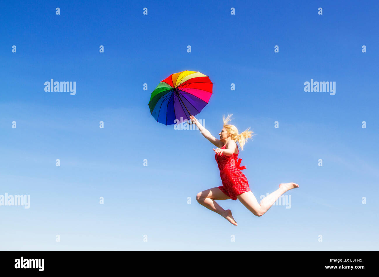 Young woman jumping with colorful umbrella Stock Photo - Alamy