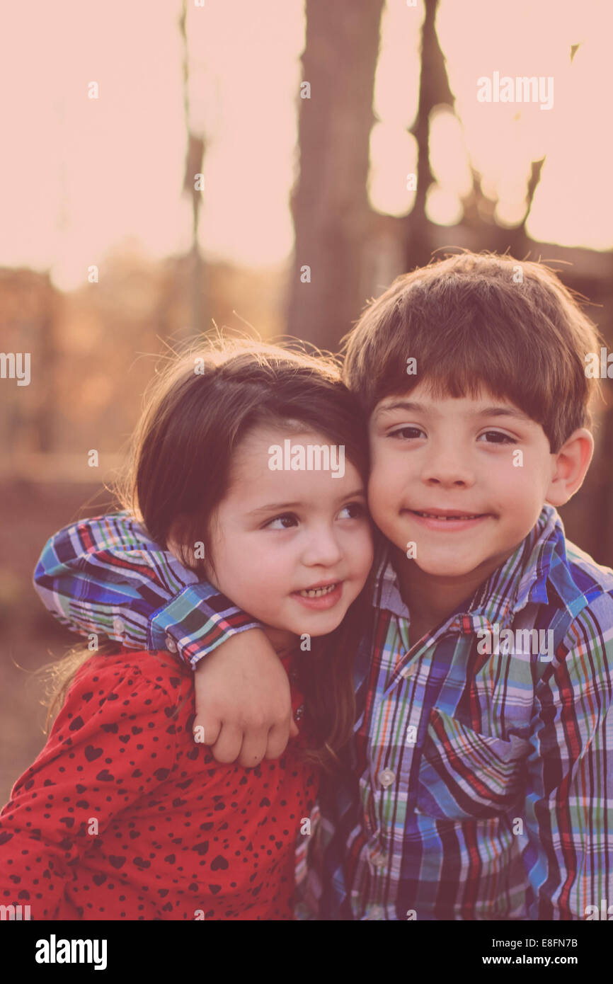 Portrait of sister and brother hugging in the park, USA Stock Photo