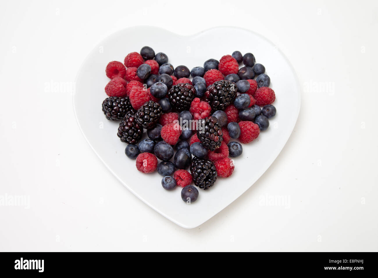 Overhead view of fresh blackberries, blueberries and raspberries on a Heart Shaped Plate Stock Photo