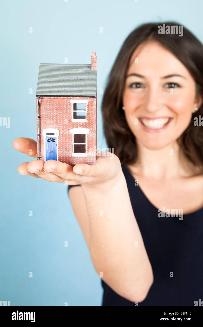 Young woman holding model house in palm of hand Stock Photo