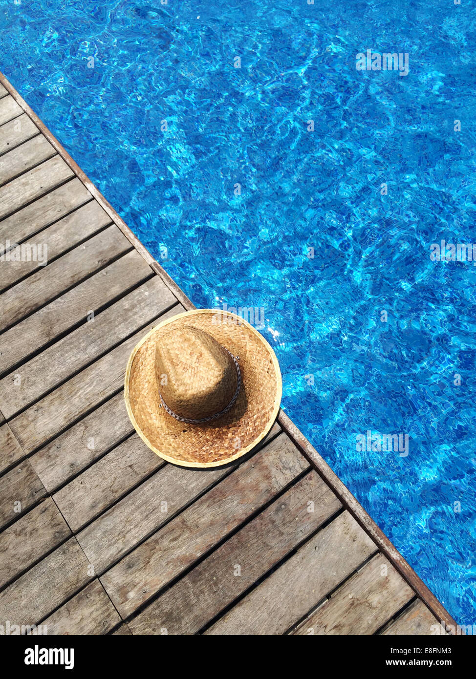 Straw sun hat by swimming pool Stock Photo