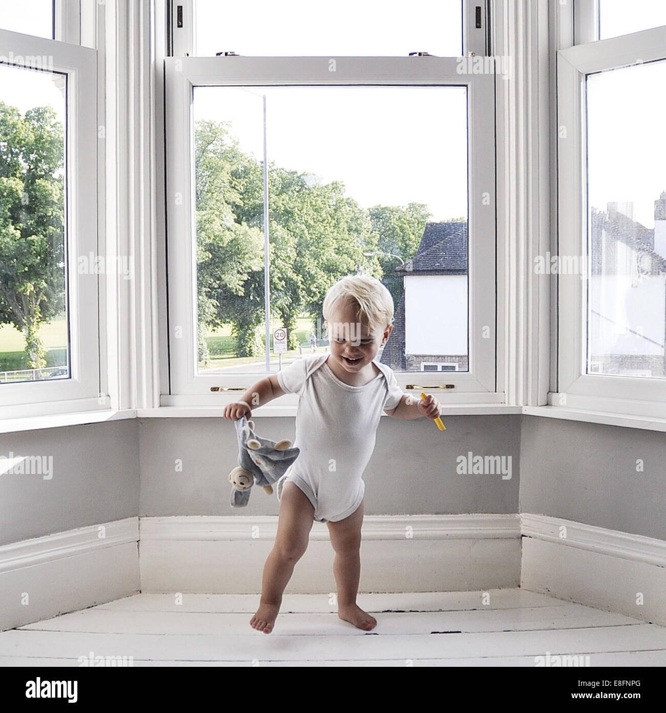 Boy dancing in living room holding toy Stock Photo