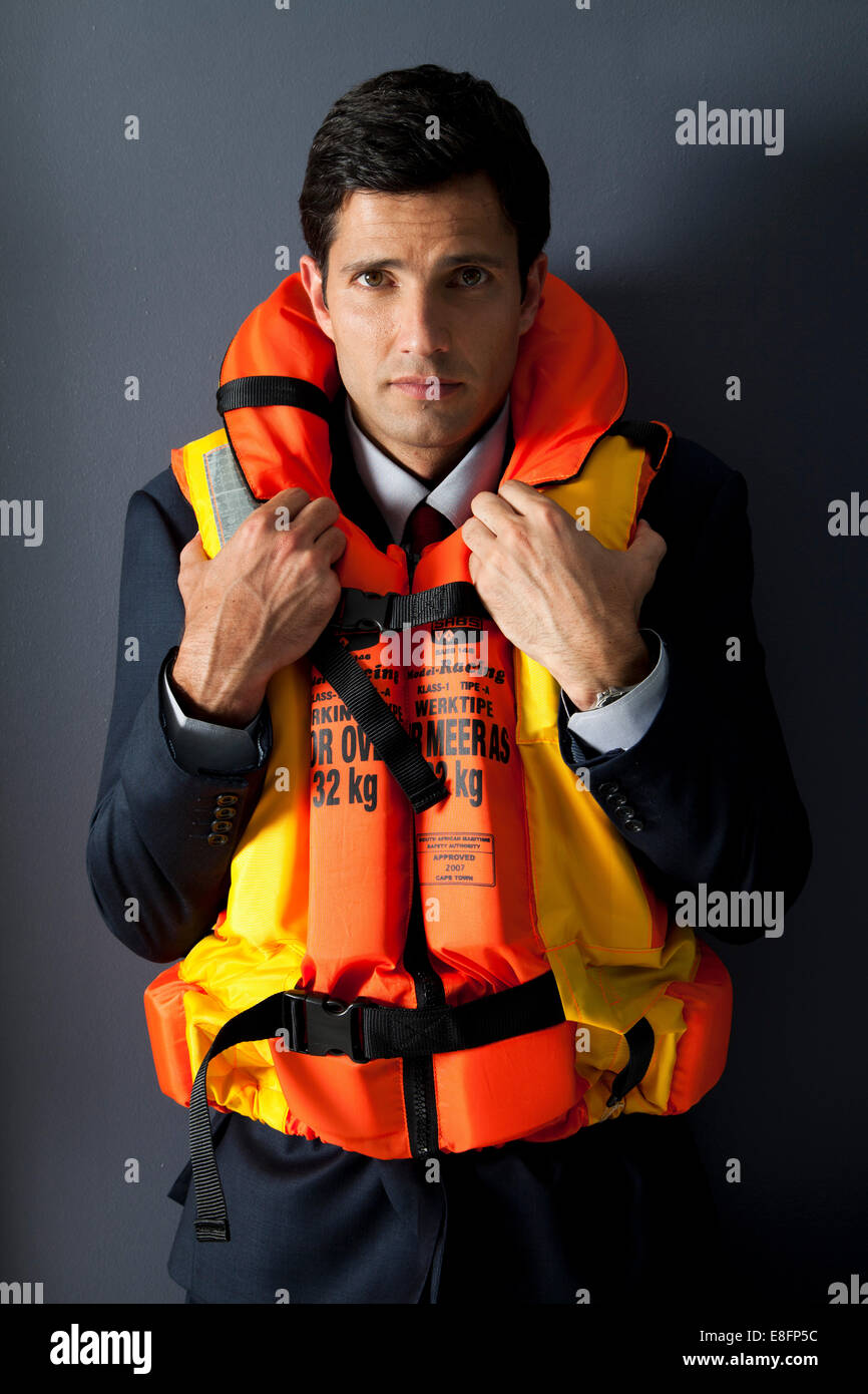 Worried businessman wearing life jacket Stock Photo