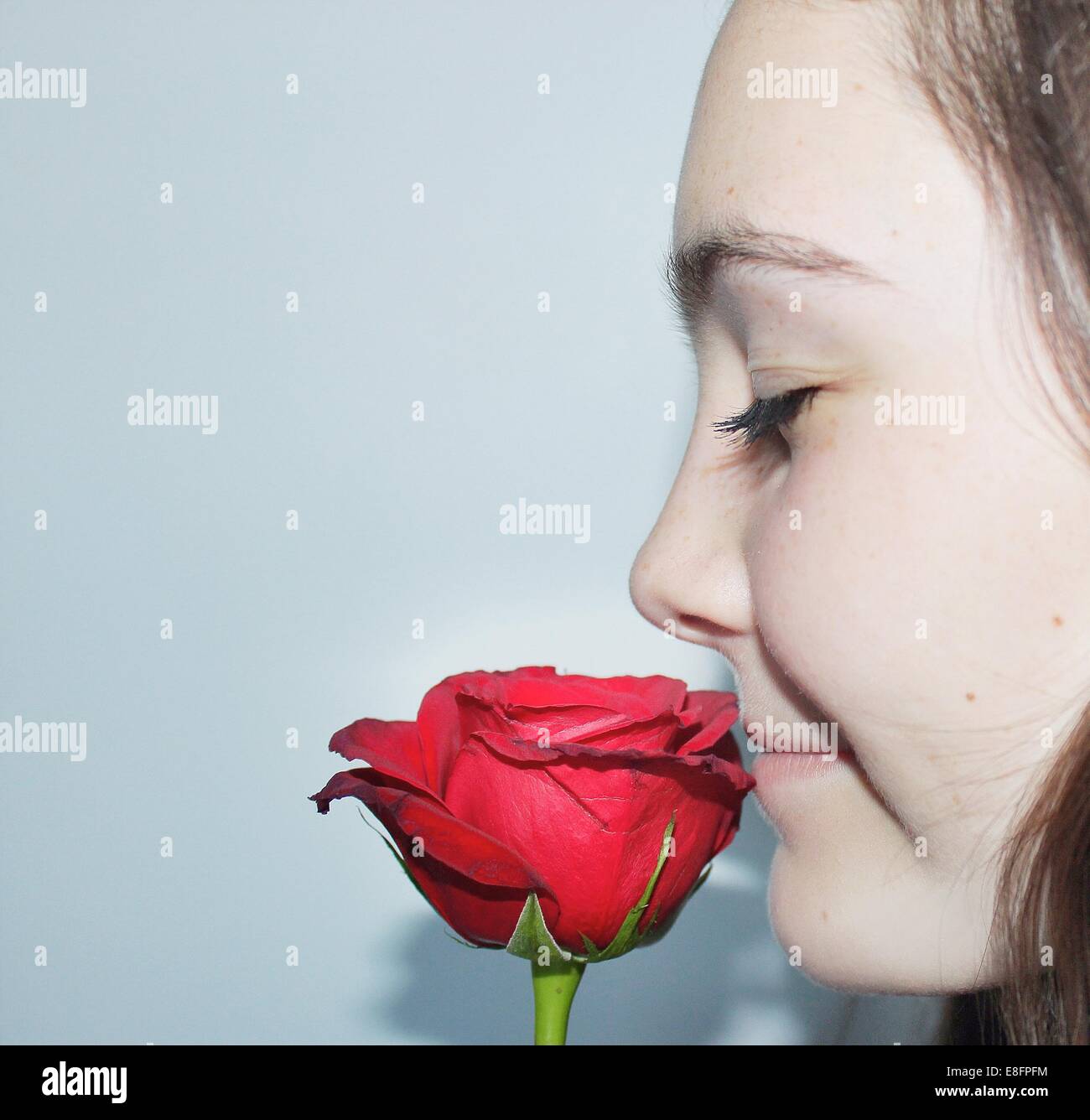 Closeup portrait of a teenage girl with eyes closed smelling a rose