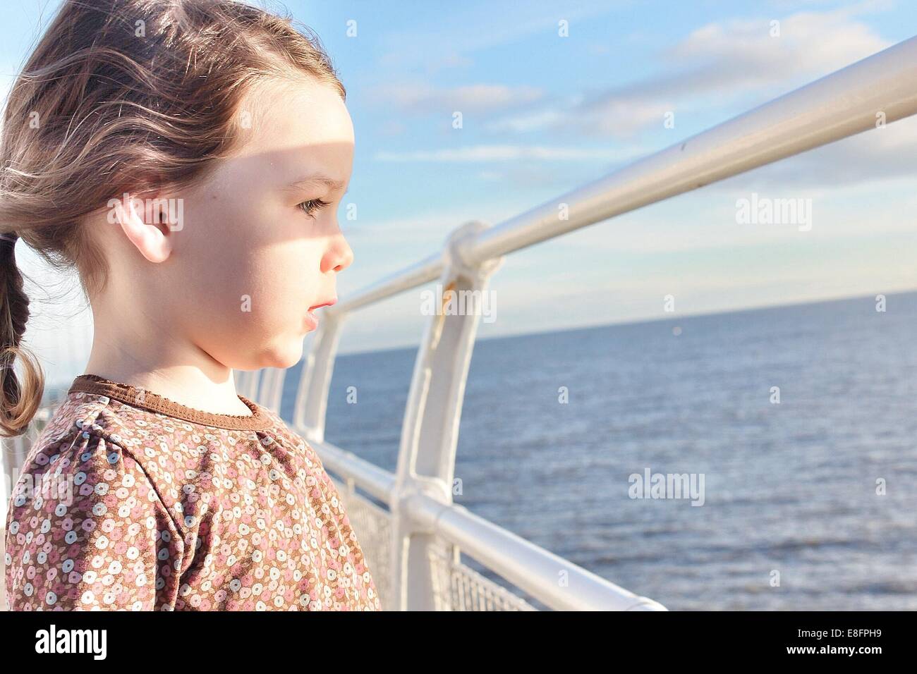 Girl standing on boat looking out to sea Stock Photo
