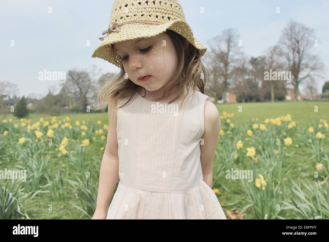 Girl wearing a straw hat standing in a field Stock Photo