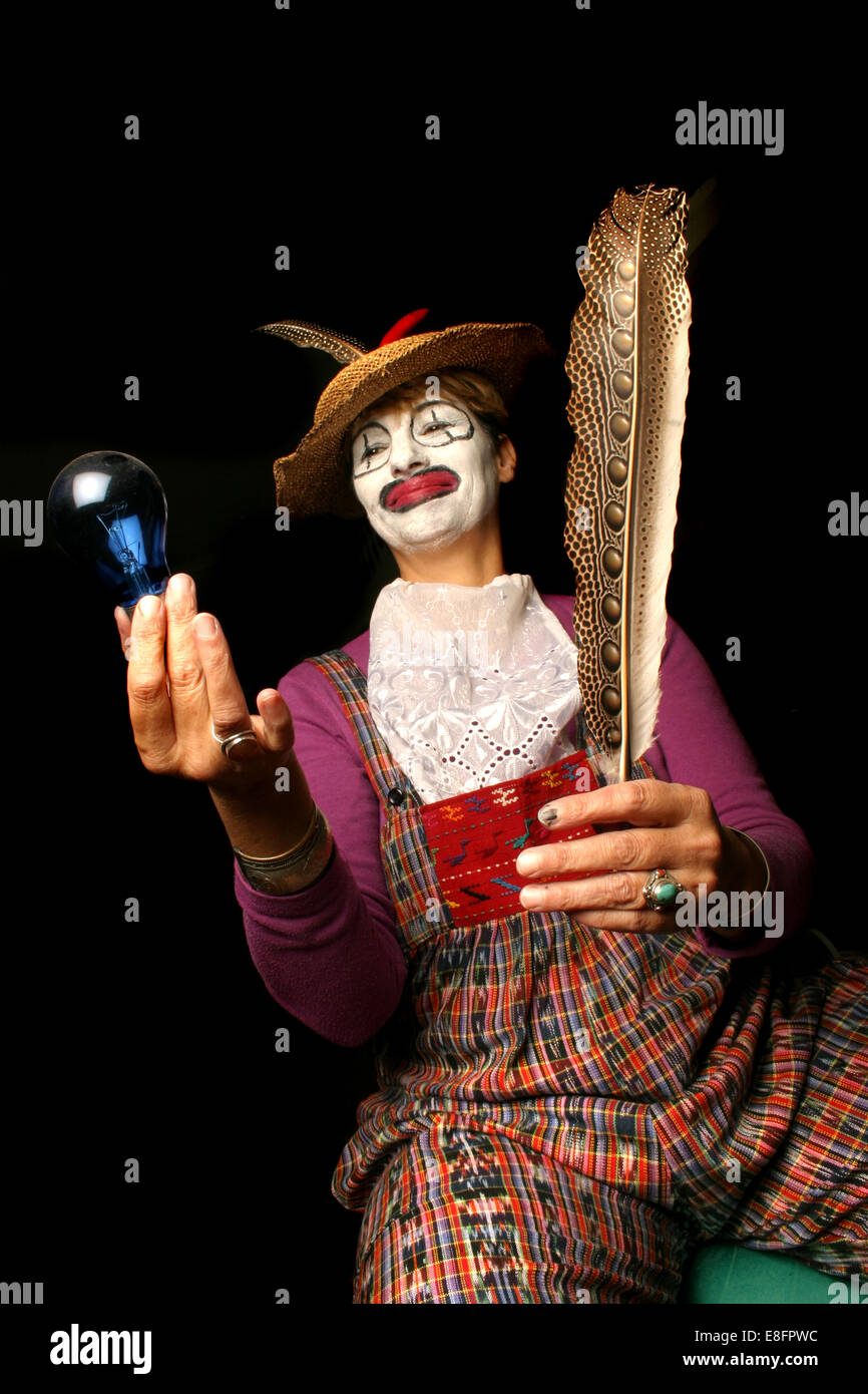 Female Clown holding light bulb and feather Stock Photo