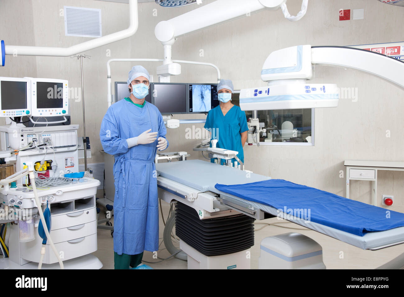 Tow doctors standing in operating theatre with robotic imaging system Stock Photo