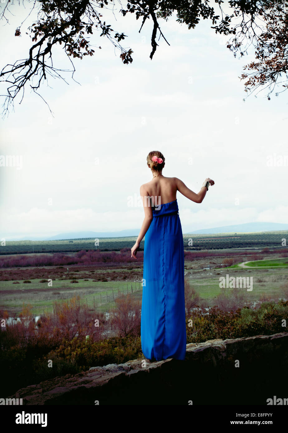 Woman wearing blue long dress standing on stone wall Stock Photo