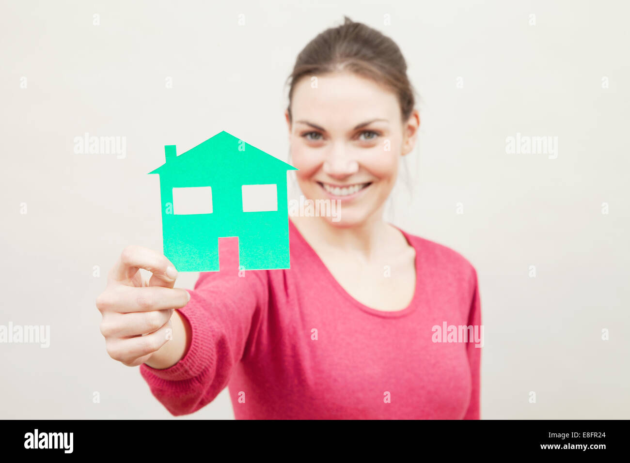 Young woman holding paper cut out of a house Stock Photo