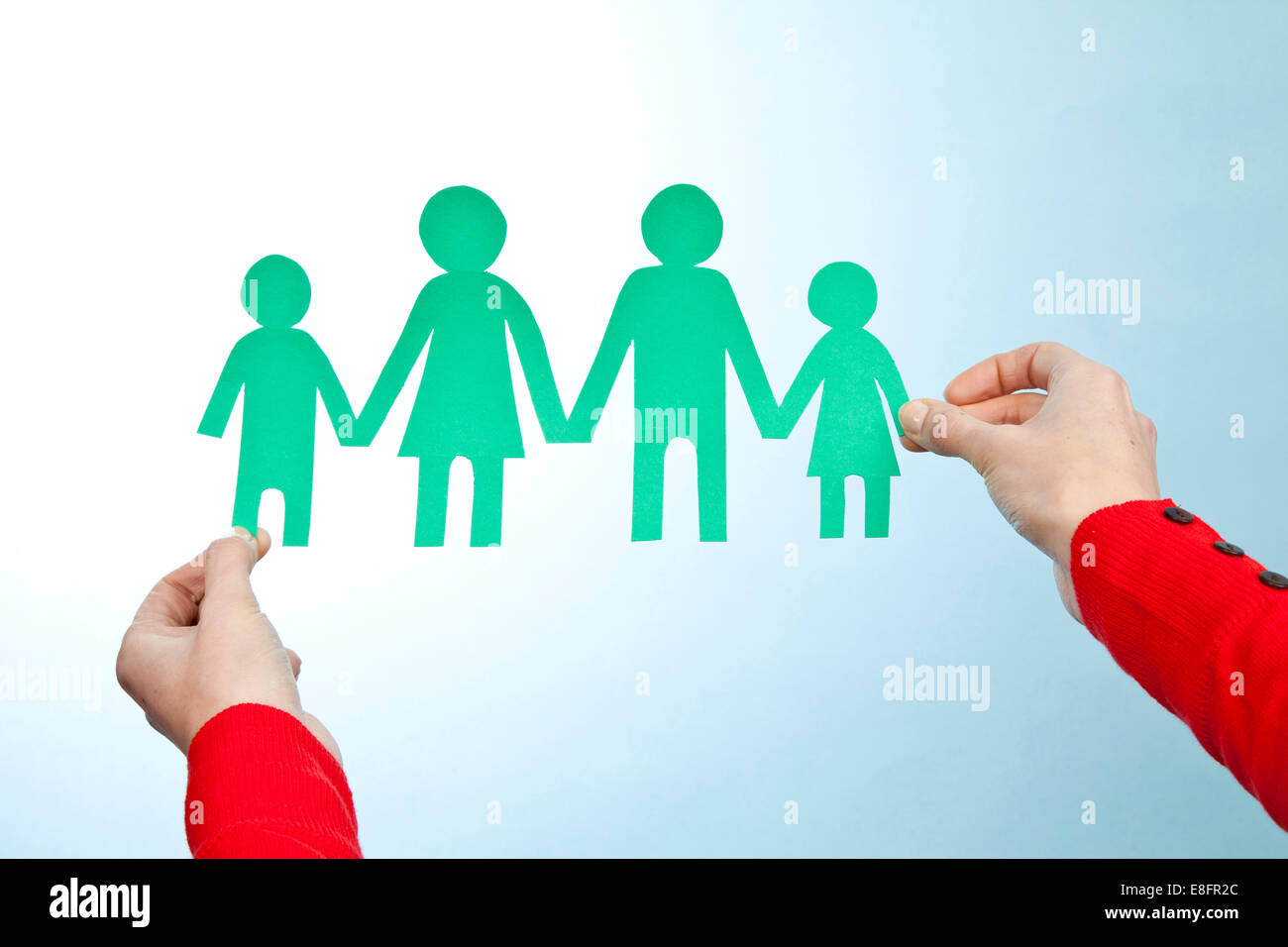 Hands holding paper cut out of family Stock Photo