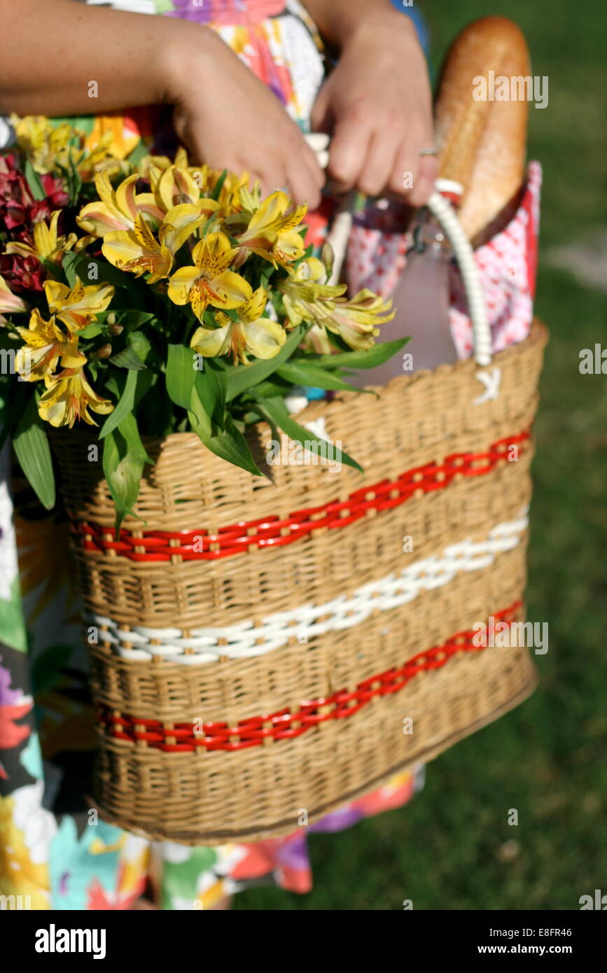 Picnic basket with flowers held by woman in floral dress Stock Photo Alamy