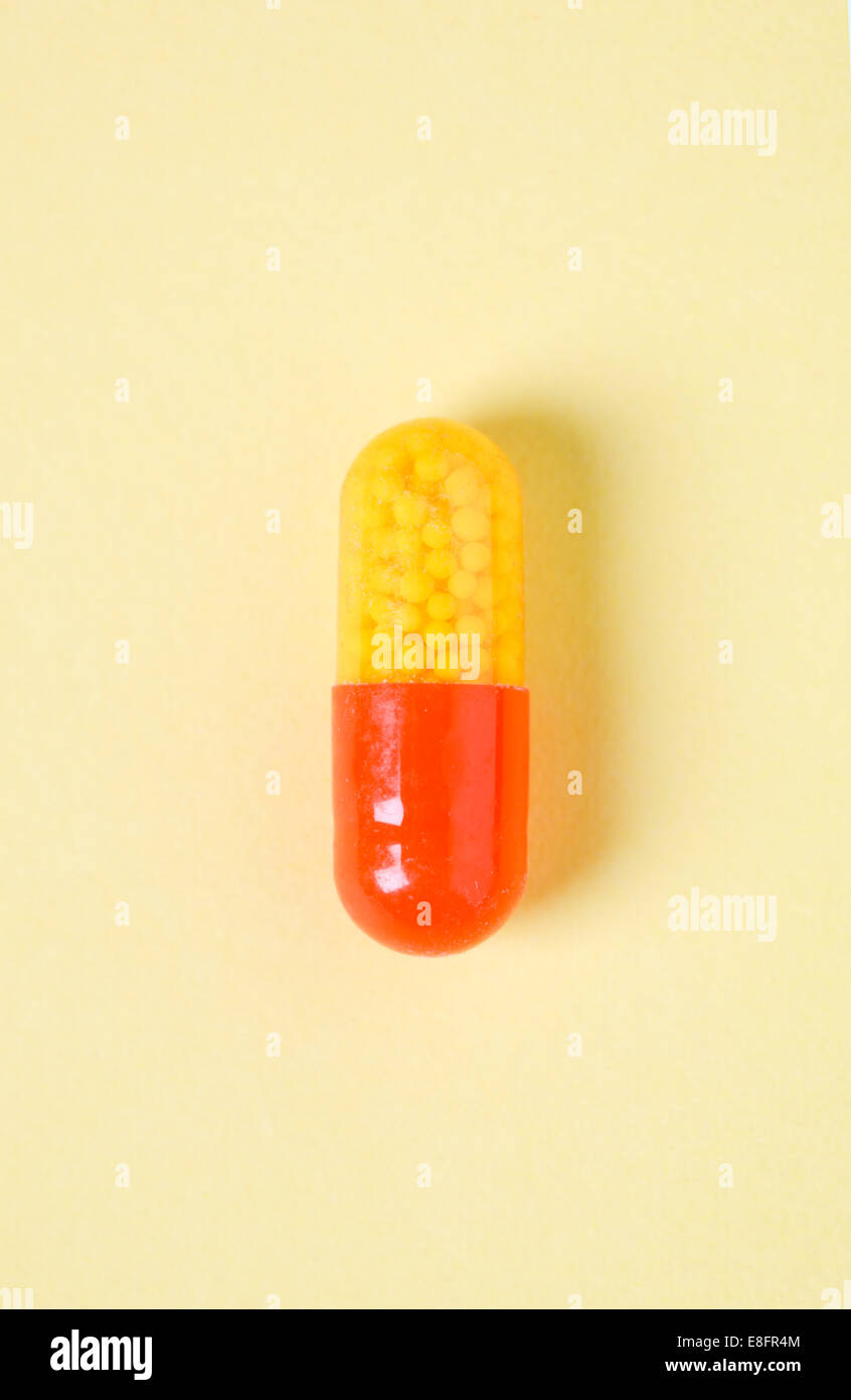 Red and yellow capsule on pale yellow background Stock Photo