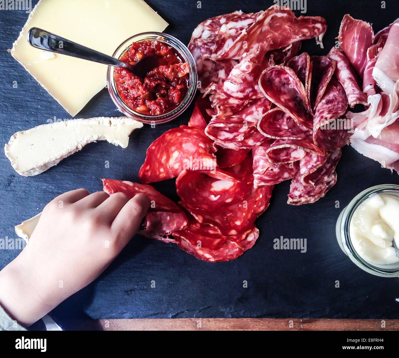 Human hand reaching for charcuterie and cheese board Stock Photo