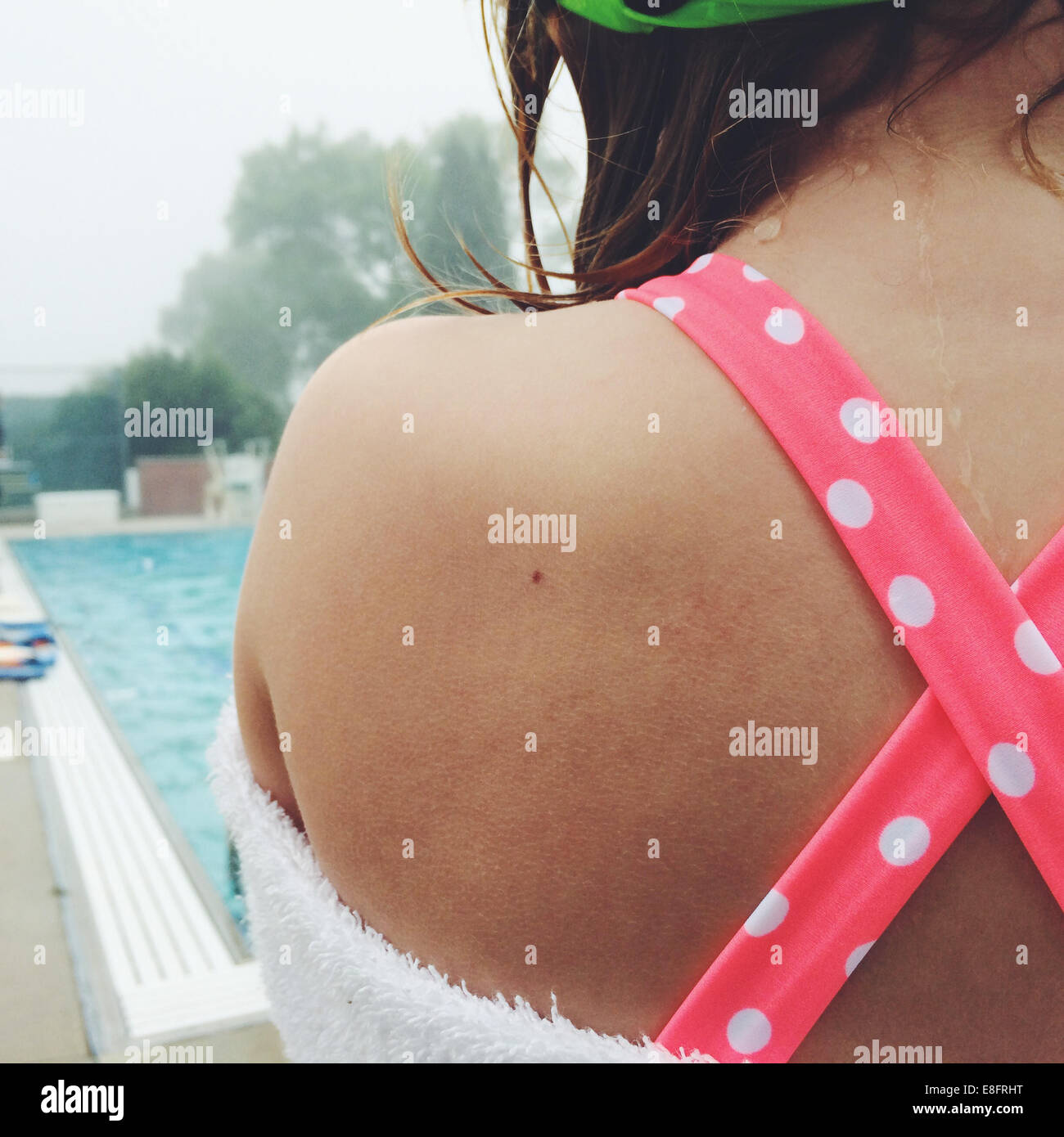 Rear view of girl (8-9) standing by swimming pool Stock Photo