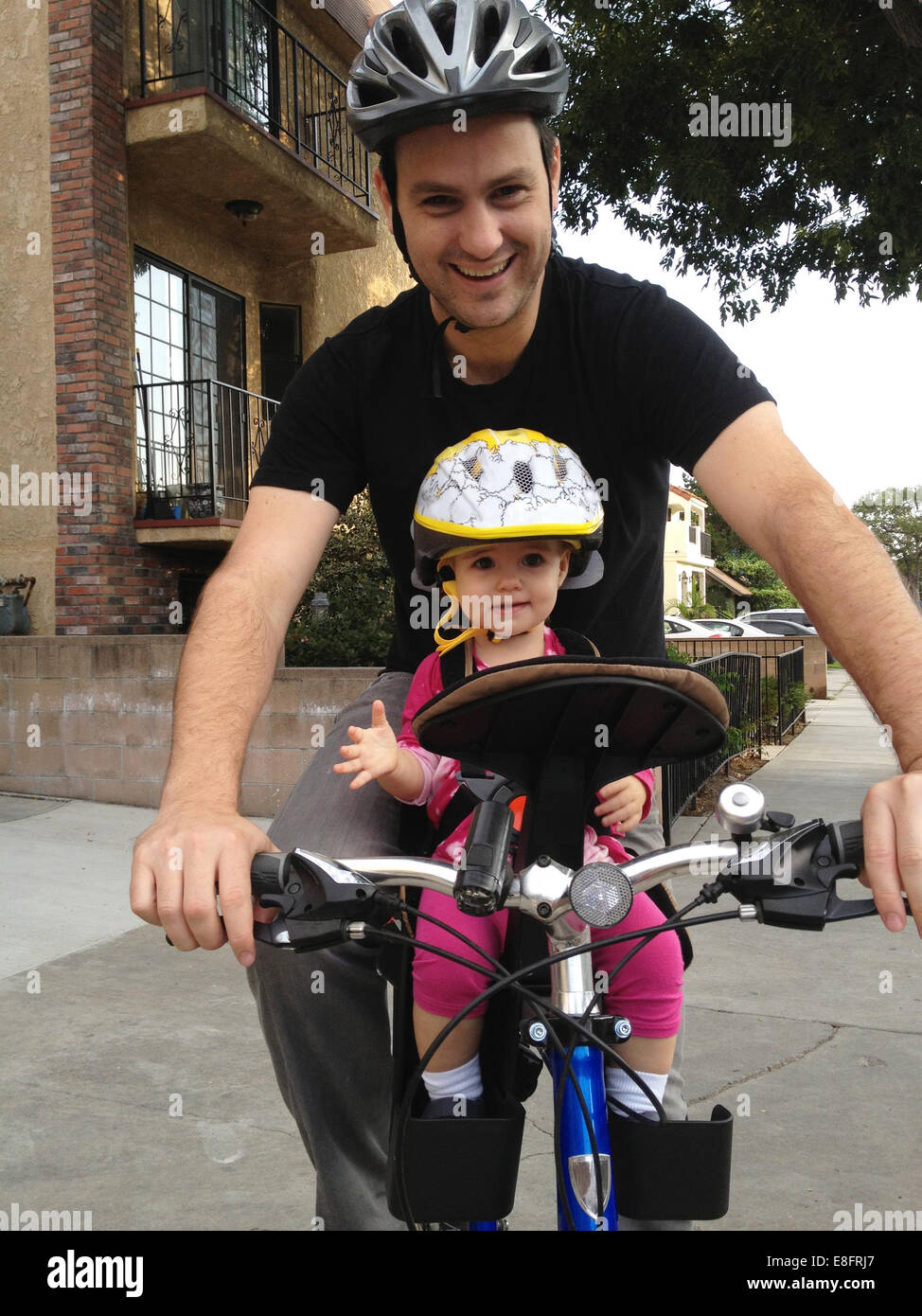 Father and daughter (18-23 months) cycling together Stock Photo