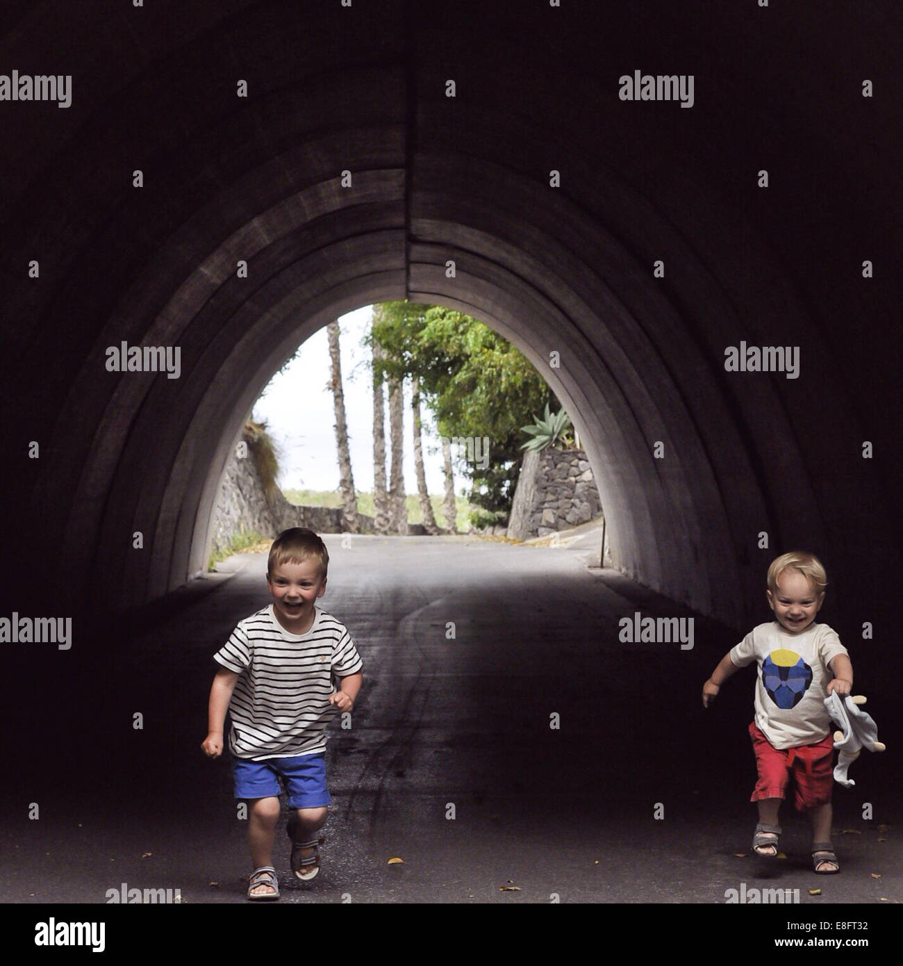 Two boys running through a tunnel Stock Photo