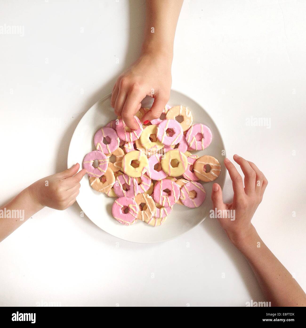 Girl's hands reaching for biscuits from plate Stock Photo