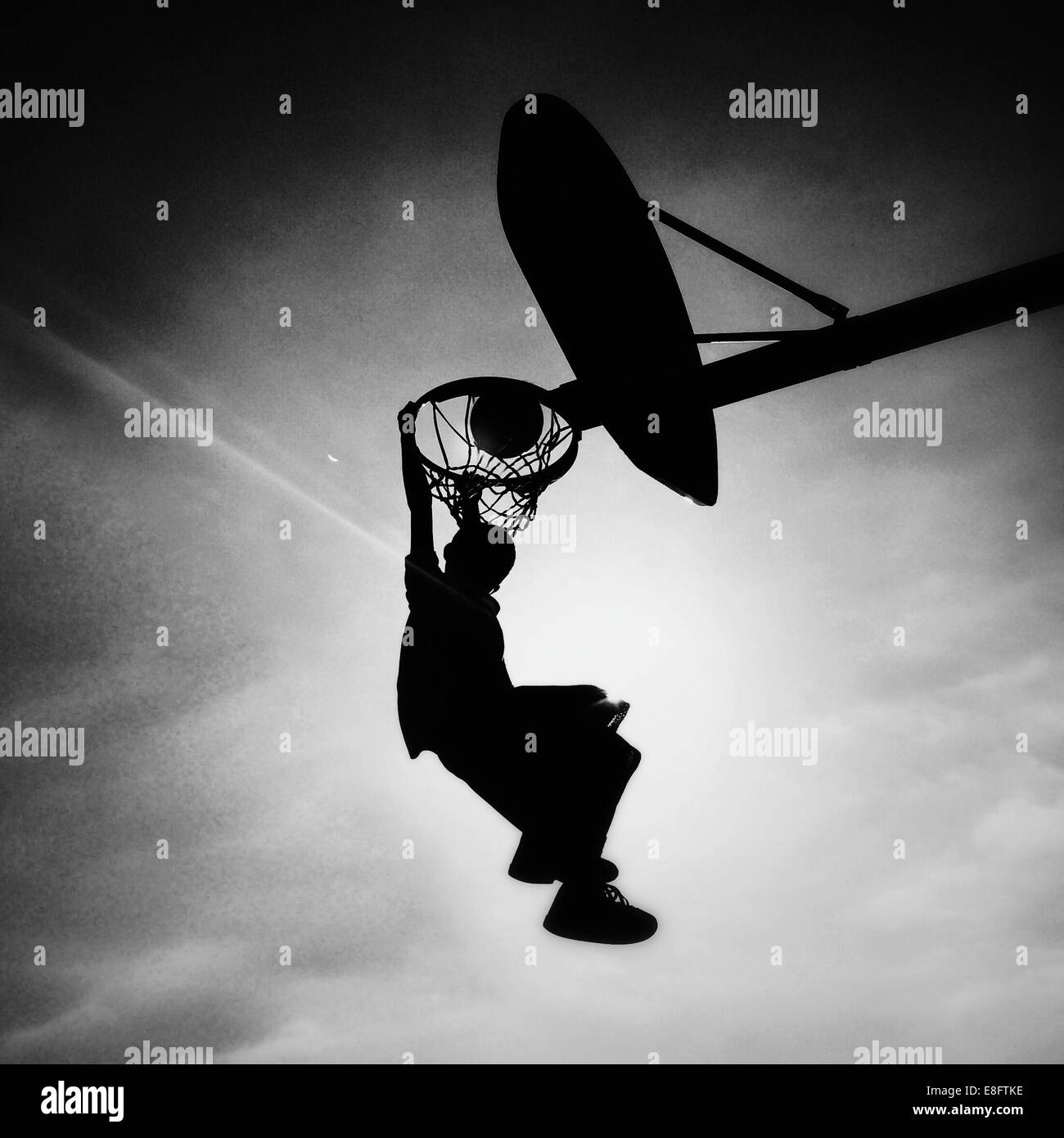 Silhouette of boy playing basketball scoring slam dunk Stock Photo