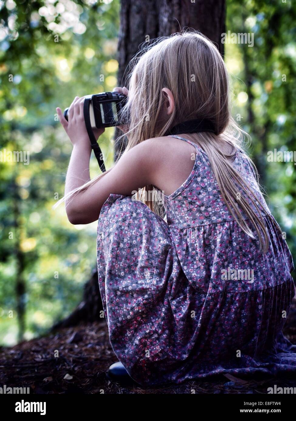 Girl crouching in the forest looking through binoculars, Sweden Stock Photo