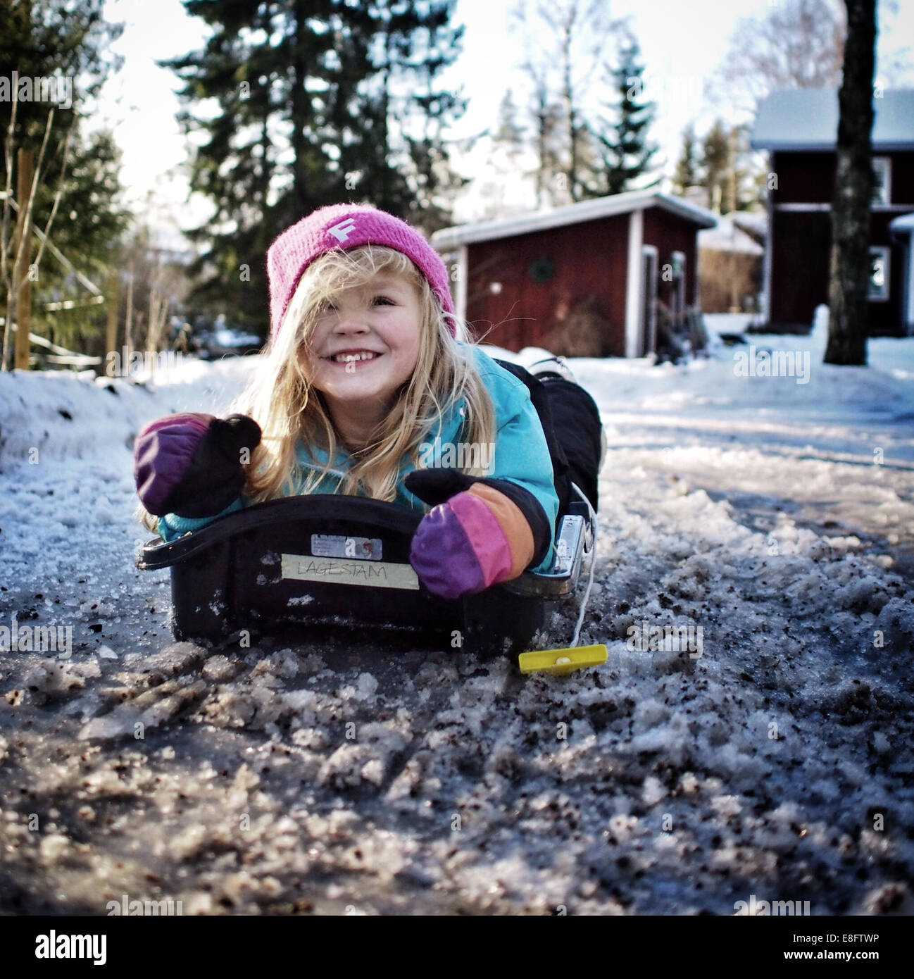 Girl lying on a sledge in the snow, Sweden Stock Photo