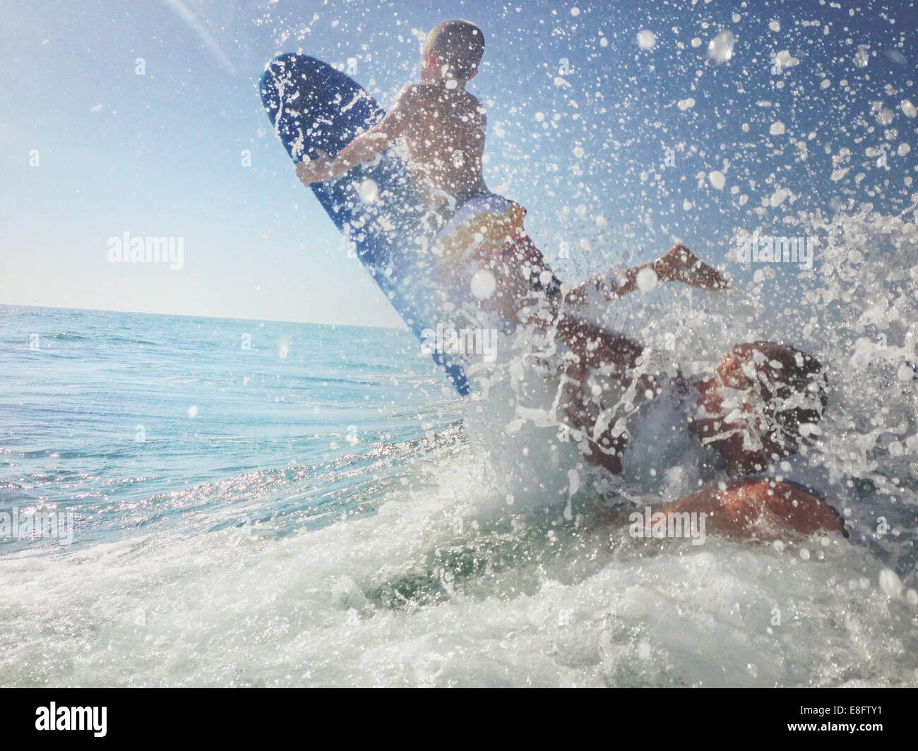 Father and son playing in ocean with surfboard, California, USA Stock Photo