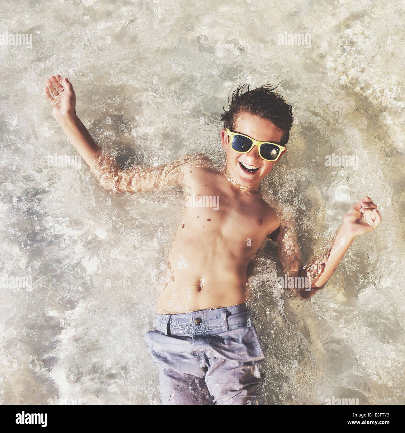 Overhead view of smiling Boy lying in shallow sea Stock Photo