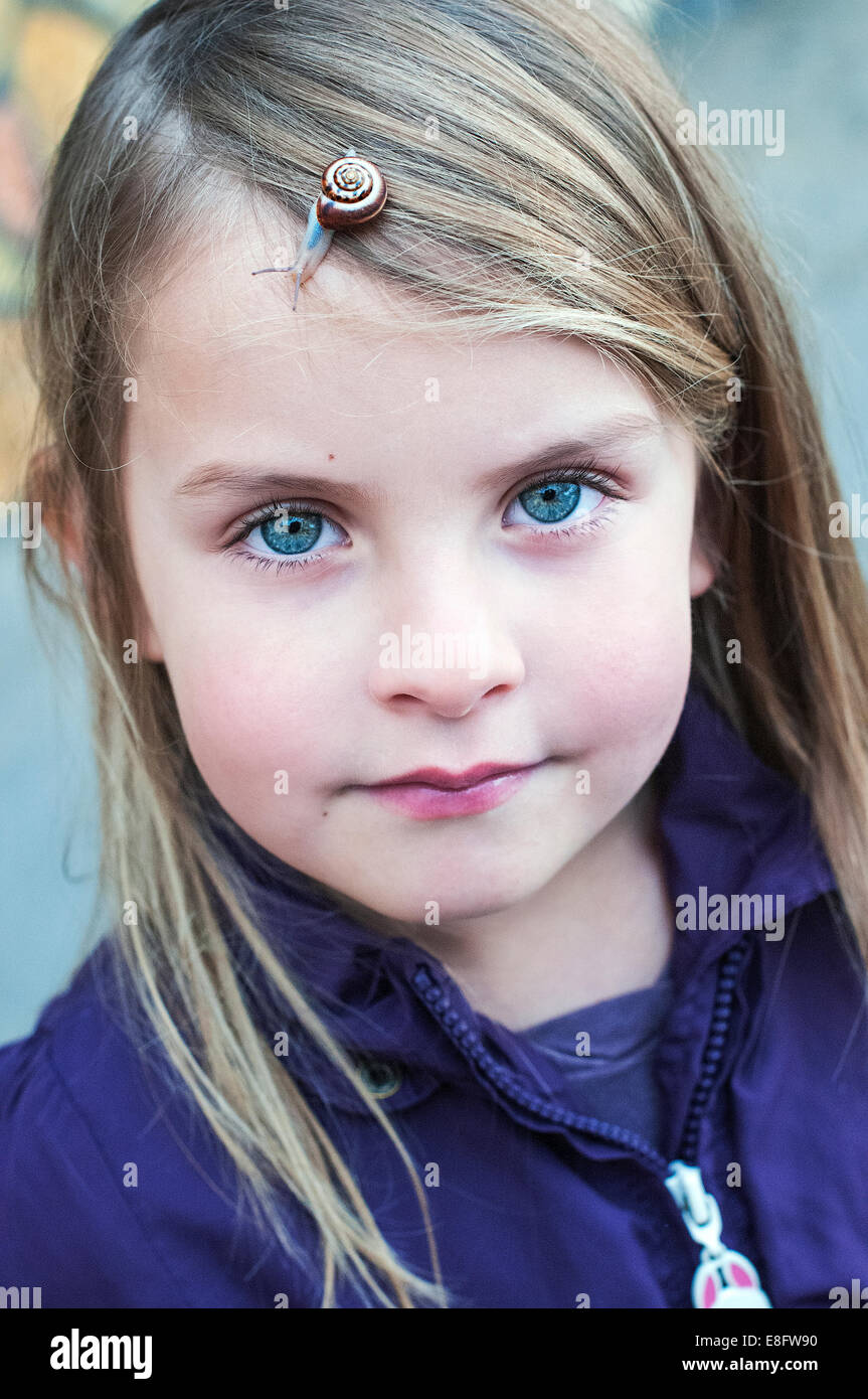 Portrait of little girl with snail in her hair Stock Photo
