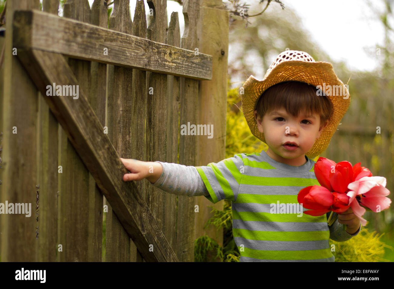 Portrait of a boy in a straw hat holding a bunch of flowers Stock Photo