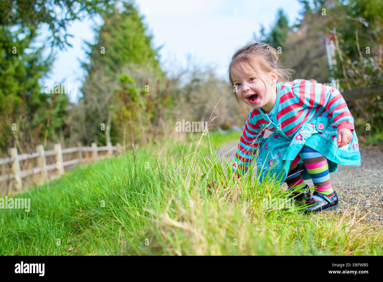 Happy girl  on a footpath bending down Stock Photo